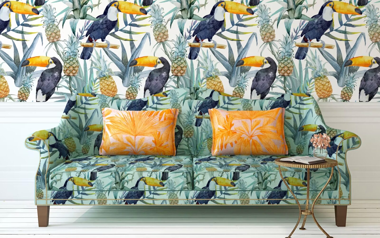 A statement sofa reupholstered in bold toucan and pineapple print fabric with orange leaf-print cushions