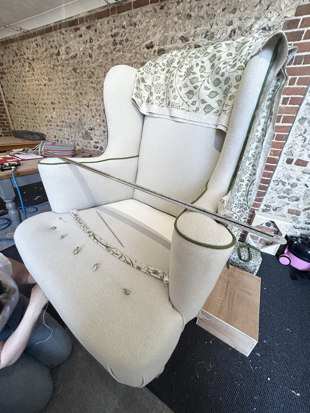 A wing chair stripped back to calico with pins