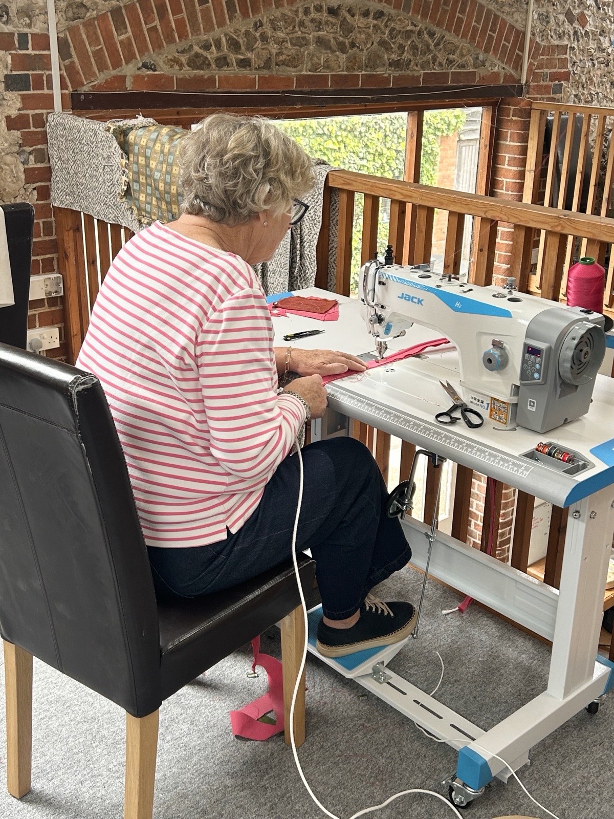 A student sewing pink fabric on an industrial machine in the studio
