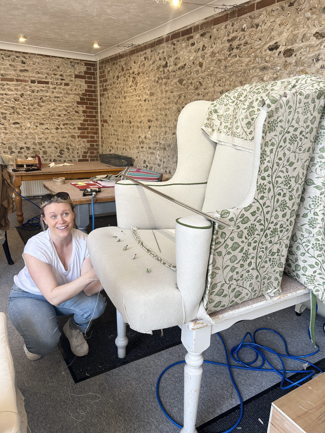 A smiling student beside a partly upholstered wing chair draped in leaf-print fabric