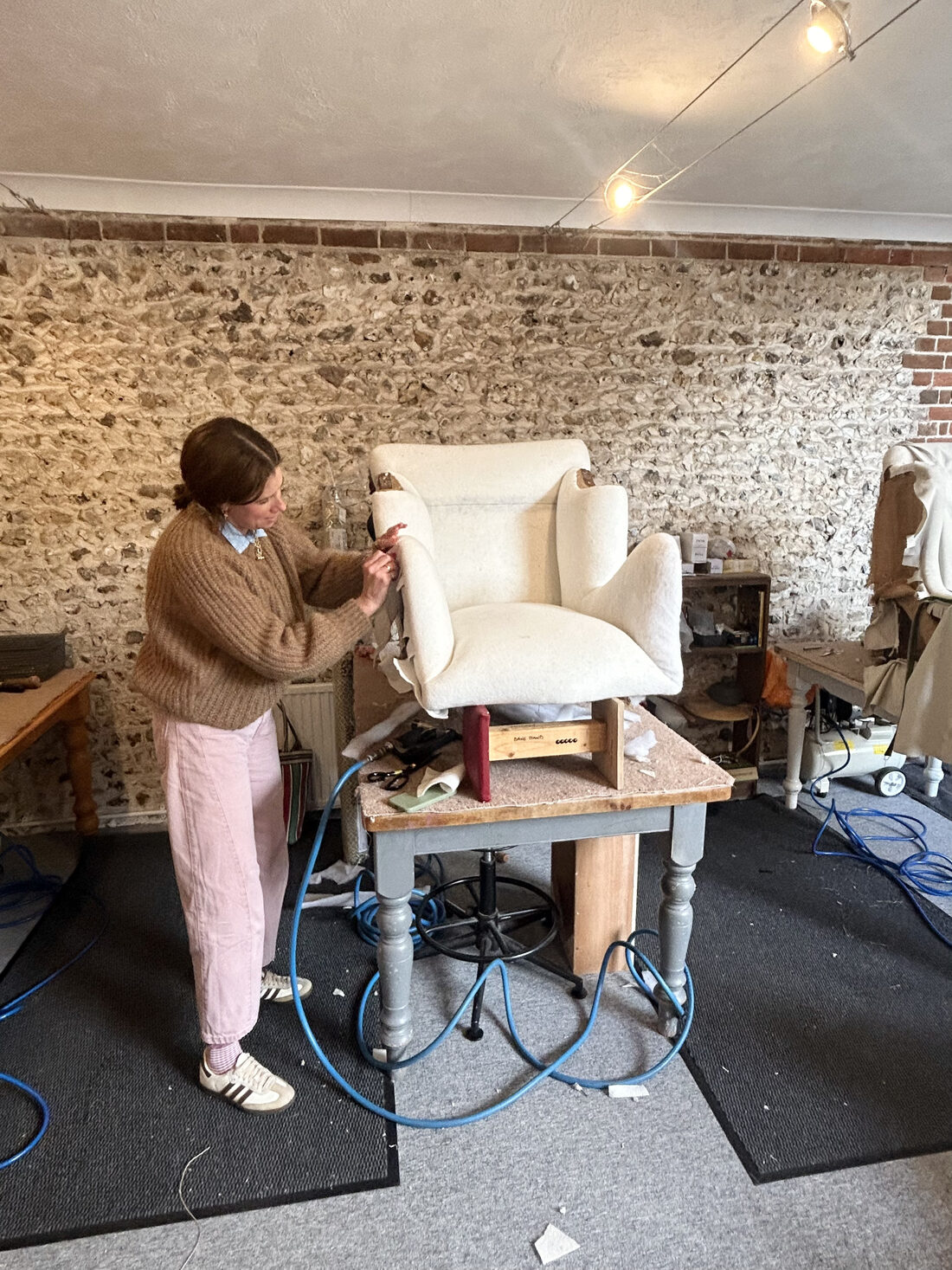 A student working on a calico-covered wing chair in the studio